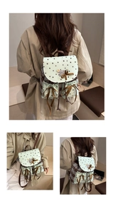 Detail of mint green star pattern backpack featuring a brown ribbon bow and wood button