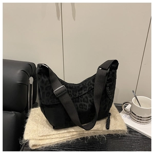 Détail du sac croissant à imprimé léopard noir avec fermeture tressée et bandoulière