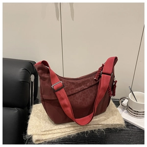 Gros plan d'un sac bandoulière léopard rouge foncé avec sangle sur une écharpe beige