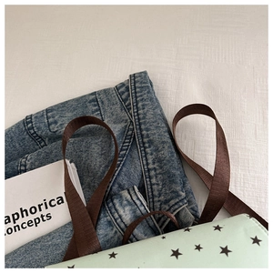 Detail of mint green canvas backpack featuring black star print and durable brown straps