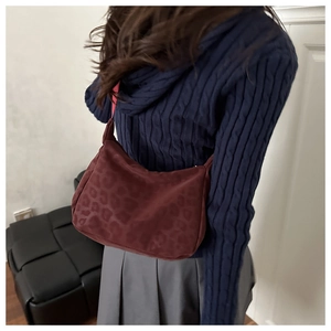 Deep burgundy leopard print tote bag styled on model with a navy sweater and pleated skirt