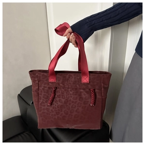 Détail d'un sac cabas léopard bordeaux avec poignées rouges et cordon de serrage tissé