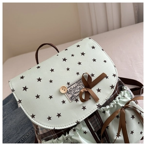 Detail of mint green backpack with star prints, bow ribbon, and wood button accent