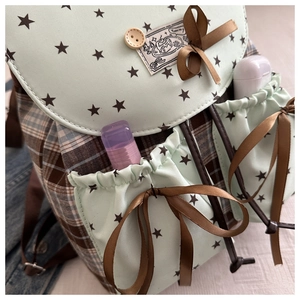 Detail of mint green mini backpack showing side pockets and cute ribbon bow decoration