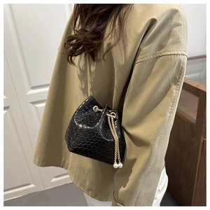 Detail of black woven bucket bag with gold chain strap and pearl drawstring charms