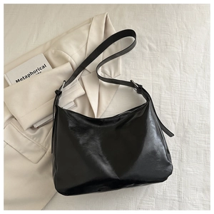 Dettaglio di una borsa tote nera minimalista in pelle cerata con fibbia in metallo argento