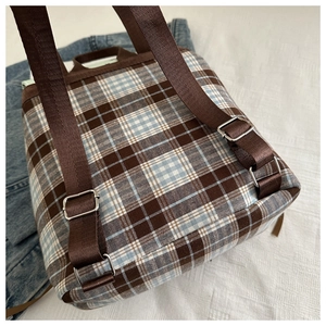Detail of adjustable brown nylon straps and silver buckles on vintage plaid backpack