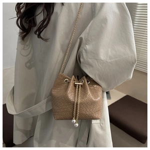 Detail of khaki woven bucket bag with gold chain and large white pearl charms