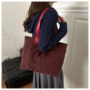 Détail du sac cabas bordeaux à imprimé léopard avec texture velours et anses rouges