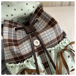Close-up of mint green backpack featuring brown plaid pattern and star hardware detail