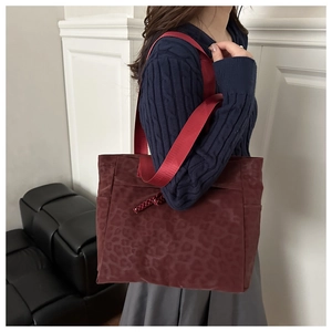 Detail of burgundy leopard print tote bag with wide strap and woven rope accent