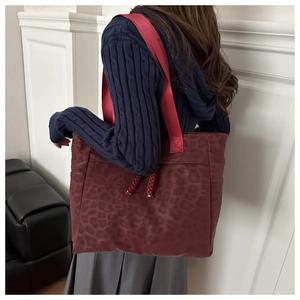 Detail of burgundy leopard print tote bag featuring woven drawstring and wide shoulder strap