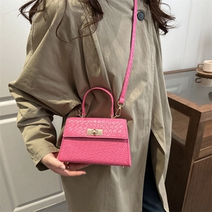 Sac bandoulière rose à texture tressée avec fermoir doré porté par un mannequin