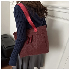 Macro view of dark red leopard print tote bag with woven straps and metal accents
