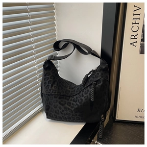 Détail du sac hobo noir à motif léopard avec zip tressé et bandoulière réglable