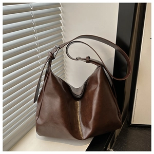 Dettaglio della borsa tote marrone scuro con trama in pelle e chiusura a zip in metallo