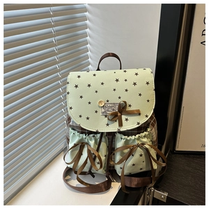 Detail of green star pattern flap and brown plaid school backpack with ribbon bows