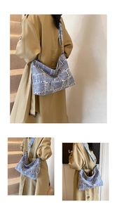 Detail of blue striped canvas tote bag with wide textured shoulder strap on model
