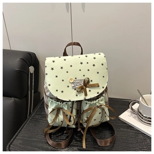Detail of mint green backpack with star patterns and brown ribbon bow decoration