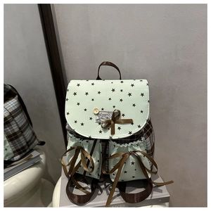 Detail of mint green backpack featuring star prints, wooden buttons and a brown silk bow