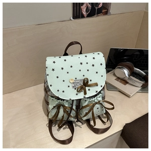 Detail of mint green mini backpack with bow and star print on a wooden desk setup