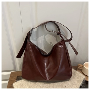 Dettaglio della borsa hobo in pelle lucida bordeaux con anello in metallo e tracolla larga