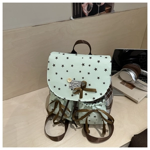 Detail of mint green star-pattern backpack featuring drawstring pockets and bow accents