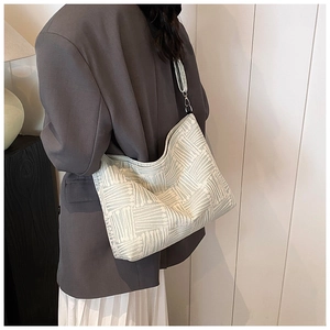 Detail of green and beige striped knit shoulder bag with metal buckle strap on a model