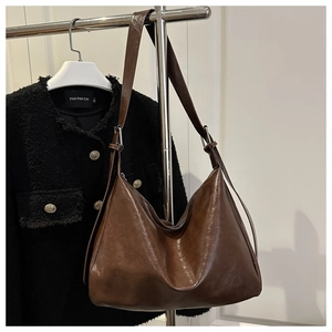 Dettaglio della borsa Hobo in pelle lucida marrone scuro con tracolla e fibbia argento