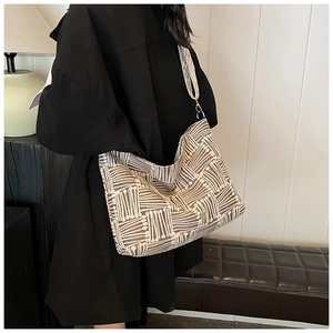 Detail of large tote bag showing textured beige and brown geometric striped woven fabric