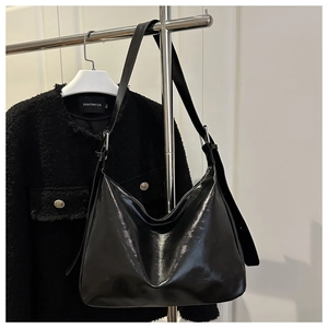 Dettaglio della borsa tote in pelle cerata nera lucida con tracolla regolabile e fibbia argento