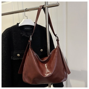 Dettaglio della borsa Hobo in pelle lucida marrone scuro con tracolla ampia regolabile