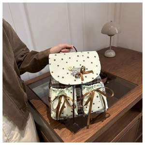Detail of vintage plaid backpack with mint green flap and bow on wooden cabinet