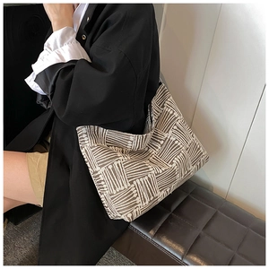 Brown and beige striped knit hobo shoulder bag shown on a model in a minimalist setting