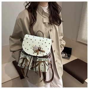 Detail of mint green backpack featuring star prints, plaid pockets and brown ribbon bows