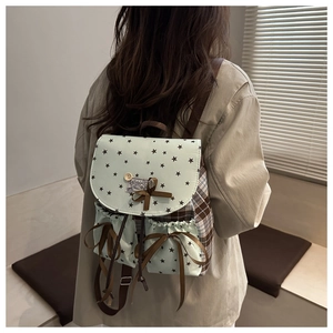 Close-up of mint green backpack with star patterns, bow detail and plaid fabric texture