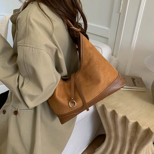 Borsa sottobraccio in pelle opaca marrone con anello metallico su trench beige
