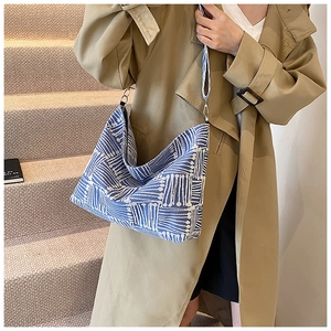 Detail of blue and white geometric canvas tote with adjustable strap on a trench coat