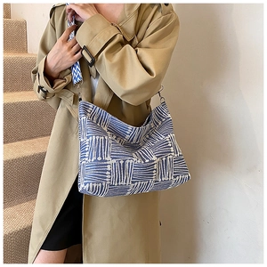 Detail of blue and white striped knit hobo bag with wide printed shoulder strap