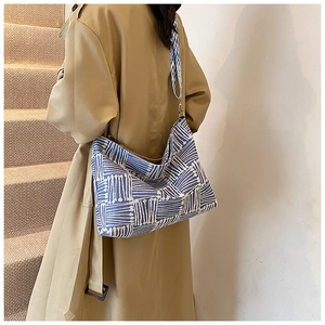 Detail of blue and white striped tote bag with adjustable strap on a shoulder model
