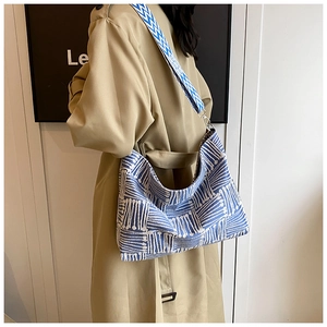 Detailed side view of a large canvas tote bag with blue geometric patterns and wide strap