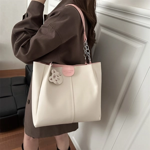 Large beige tote bag with pink trim, metal chain straps, and a cute tiger charm