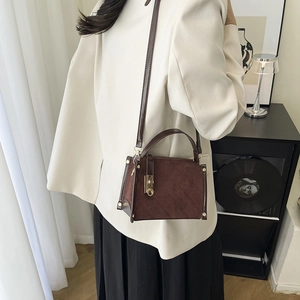 Deep coffee quilted crossbody bag with gold twist lock on model wearing white blazer