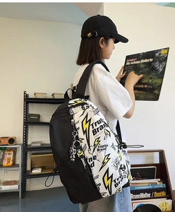 Side view of graffiti backpack with yellow lightning print and trendy pendant