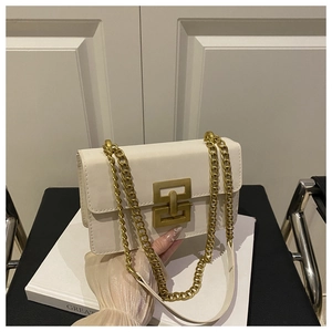 Close-up of cream rectangular shoulder bag featuring a gold interlocking geometric lock