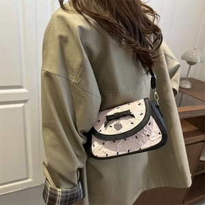 Sac bandoulière plissé rose avec imprimés nœuds noirs et pendentif cœur argenté