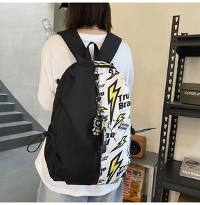 Rear view of graffiti backpack featuring lightning print and astronaut charm on model