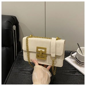 Detail of cream leather crossbody bag with gold geometric lock and chain strap