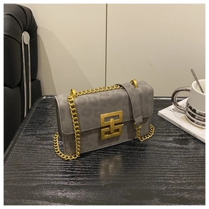 Detail of grey leopard print crossbody bag with gold chain strap on a dark wood table