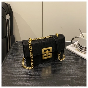 Close-up of black textured crossbody bag with gold geometric lock and chunky chain strap